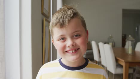 portrait of caucasian boy smiling while standing in the living room at home