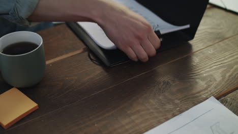 Male-hands-opening-folder-and-getting-paper-documents-at-meeting-table