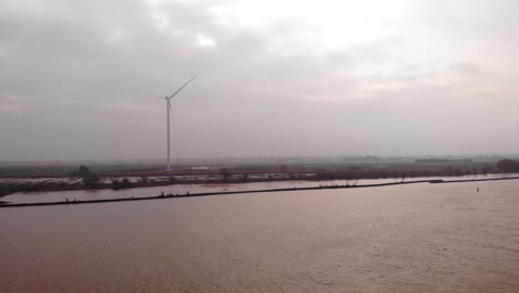 aerial view over oude maas with single wind turbine seen on overcast day in distance in barendrecht