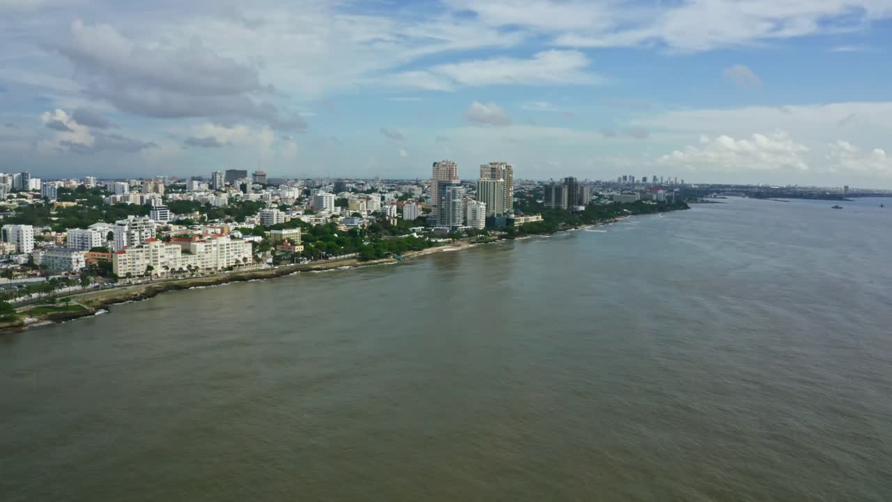 Vista aerea da drone del Malecón e della costa di Santo Domingo. L'estesa area urbana incontra il Mar dei Caraibi sotto un cielo parzialmente nuvoloso, Repubblica Dominicana