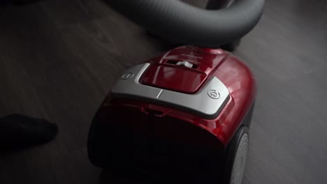 man uses foot switch to turn on canister vacuum on laminate floor