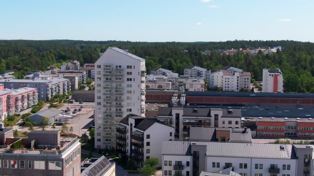 Vidsträckt drönarvy över moderna höghus och låghuslägenheter med grön skog i bakgrunden i Gustavsbergs förort. Perfekt för urbana skandinaviska bilder.