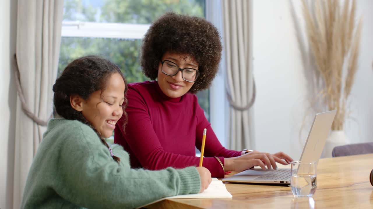 African American family at table, daughter asking and father bringing coffee, pointing at laptop
