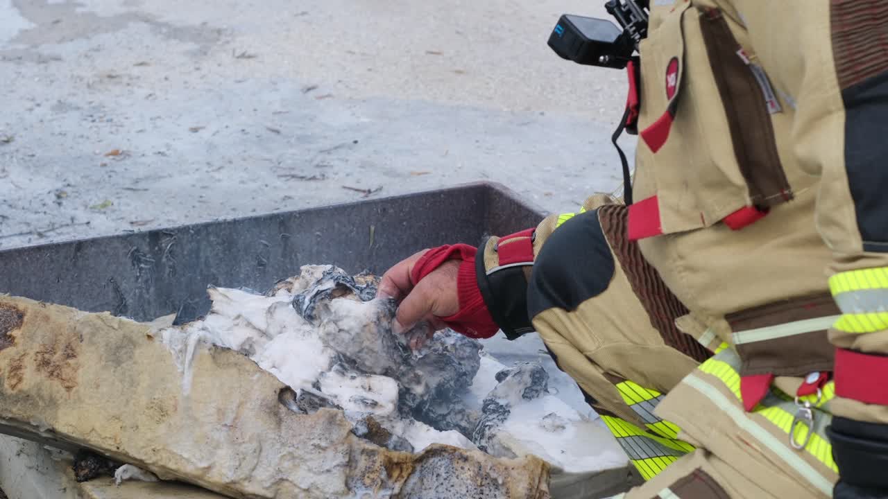 Firefighter Inspecting Burned Materials After Fire Drill