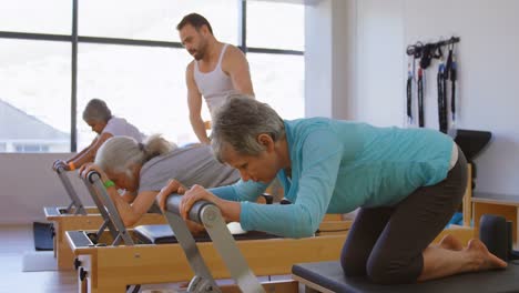 Trainer-assisting-senior-women-while-performing-yoga-4k