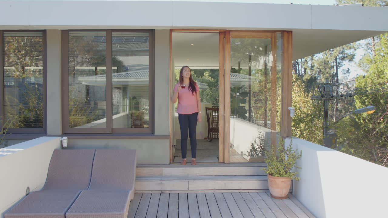 Standing on wooden deck, woman holding smartphone and smiling at camera