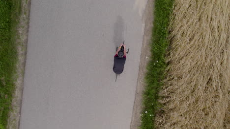 Cyclist-race-on-asphalt-in-rural-area-next-to-wheat-field