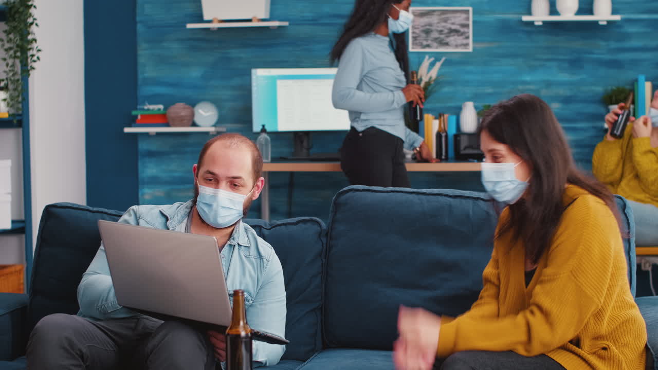 Man with sitting on sofa holding laptop talking with woman
