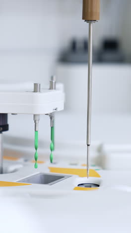 long metal needle moving from one slot to another. advanced equipment working in the science laboratory for blood test. vertical video