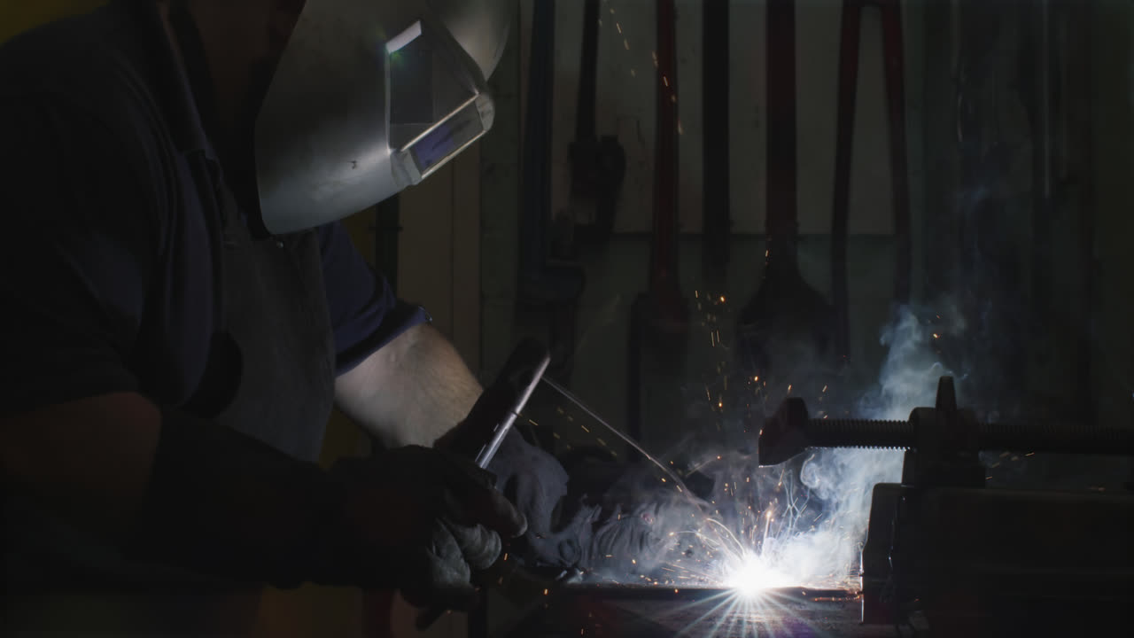 Caucasian male factory worker at a factory standing in a workbench, welding
