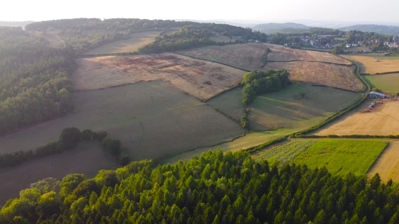 Retreating Aerial View with Rural English Village in Background with Farmed Ploughed Fields with Deep Shadows from Evening Sunlight