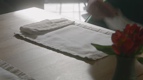 table setting with flowers and hand placing placemat