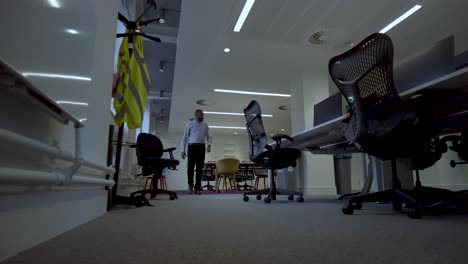 view of a man walking through a well lit modern conference room, preparing for a conference meeting with a stand for keeping coats on the right side of the video