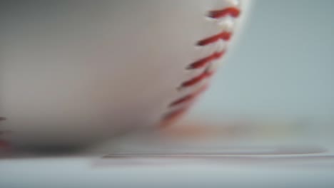 cinematic macro shot of a rotating white base ball, close-up on red stitches, baseball rotate, professional studio lighting, smooth slow motion 120 fps close-up