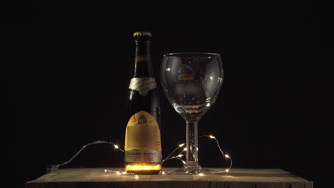 belgian blonde beer bottle and glass with string lights