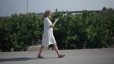 woman walking in a citrus grove and using a phone