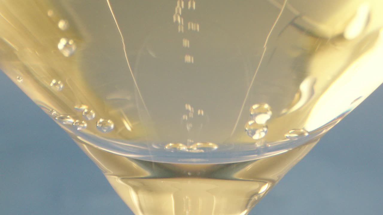 Primo piano macro: un bicchiere da cocktail pieno di ouzo, con bollicine che salgono.