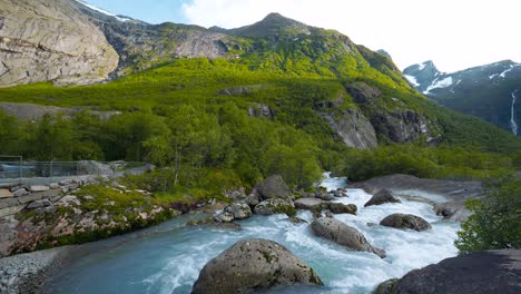 briksdalsbreen mountain river, norway. volefossen glacier water flowing through lush nature forest.