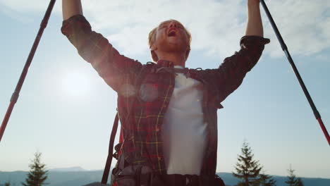 happy hiker with trekking poles raising hands and celebrating