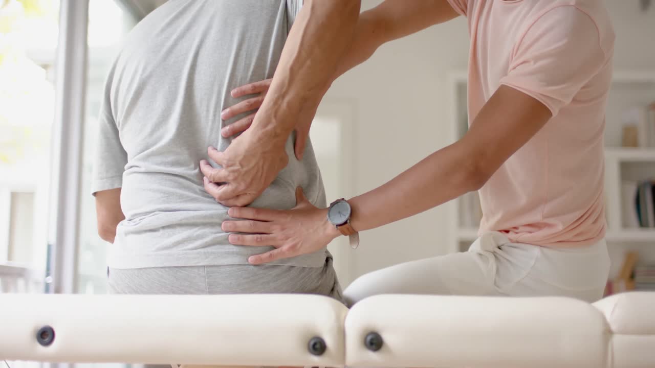 fisioterapeuta masculino diverso examinando a un paciente masculino anciano, en cámara lenta