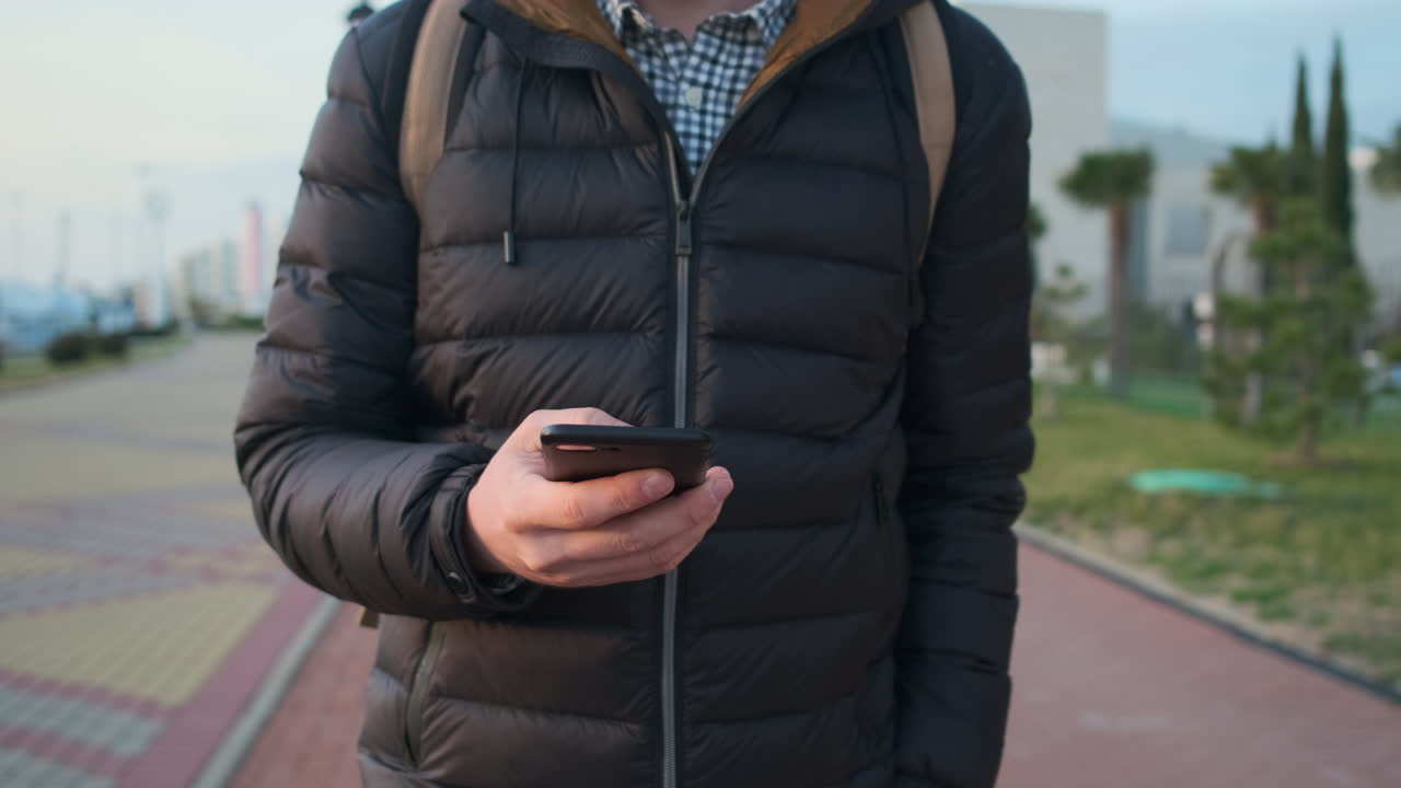 uomo che usa uno smartphone mentre cammina