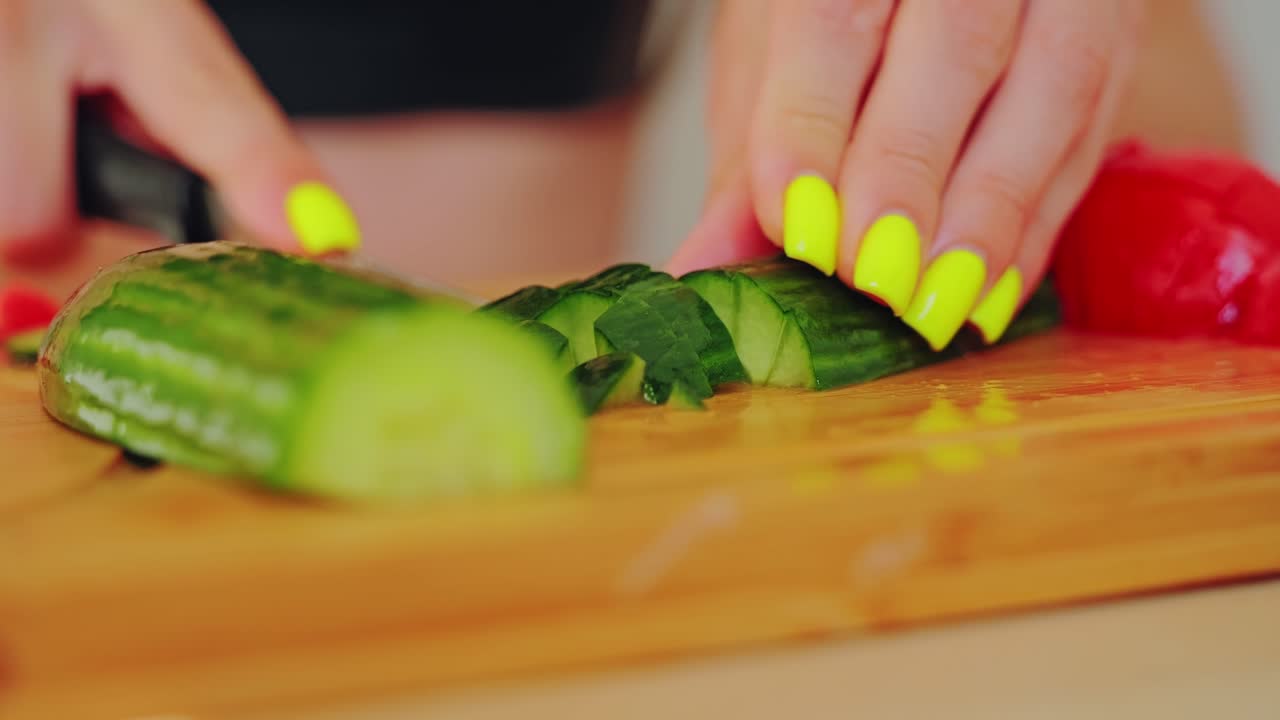 Detailed slow motion close up of woman slicing fresh cucumber on wooden board
