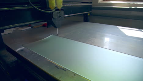 big machine-tool making picture on the glass part of a door. modern plant for doors producing.