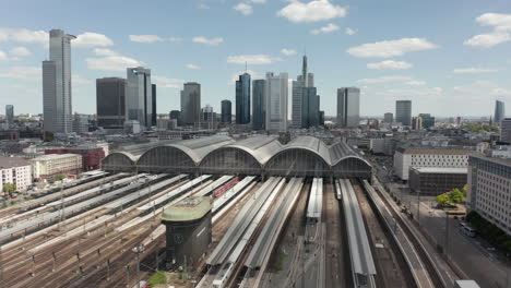 AERIAL:-Forward-Flight-over-Frankfurt-am-Main,-Germany-Central-Train-Station-Train-Tracks-with-Skyline-View-on-beautiful-Summer-Day-with-little-Traffic-due-to-Coronavirus-Covid-19-Pandemic