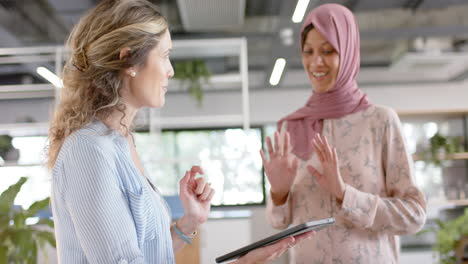 Happy-diverse-creative-female-colleagues-in-discussion-using-tablet-in-office,-slow-motion