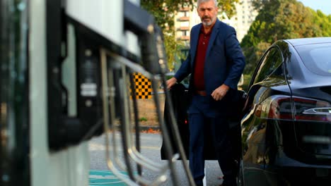 Businessman-getting-out-of-car-at-charging-station-4k