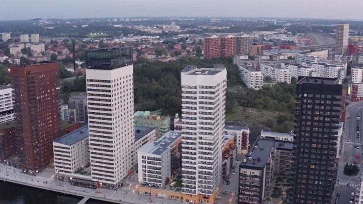 Riprese drone di quattro edifici residenziali a molti piani con design e architettura moderni ad Årstadal, Stoccolma, al tramonto con condomini sullo sfondo