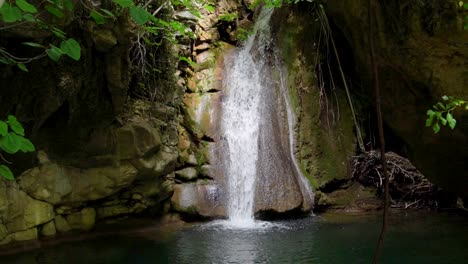 Cámara-Lenta-De-La-Cascada-De-Kefalogourna,-Rodeada-De-Vegetación-Verde-Y-Rocas-Cubiertas-De-Musgo,-Luz-Del-Sol-Brillando,-Isla-De-Thassos,-Grecia