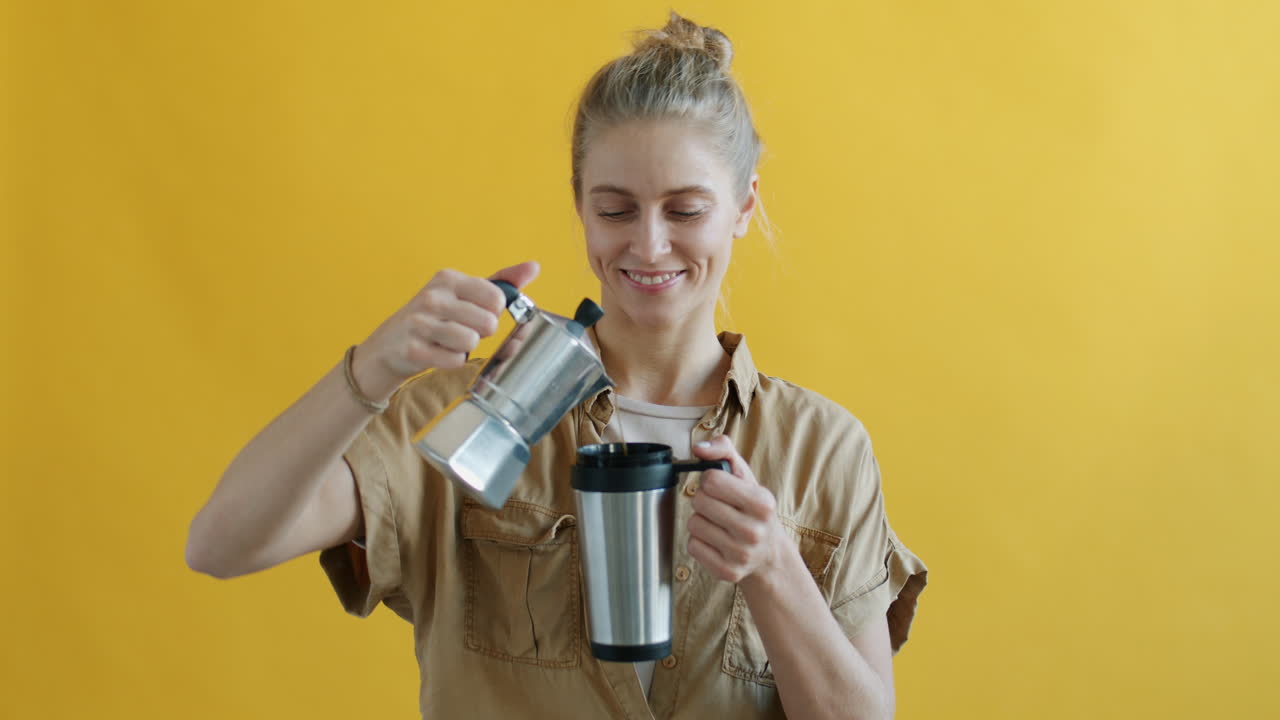 Woman Pouring Coffee from Espresso Maker into Travel Mug