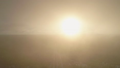 Aerial-through-morning-fog-to-reveal-highway-going-through-frozen-forest,-4K