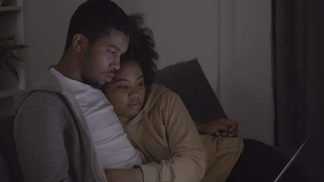 young couple watching a film attentively on the laptop