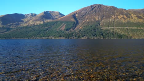 low slow flight over shoreline clear water of loch lochy scottish highlands