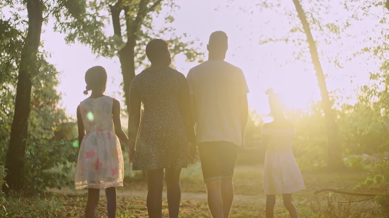 A family walks hand-in-hand through a sunlit path