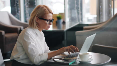mujer trabajando en una computadora portátil en un café