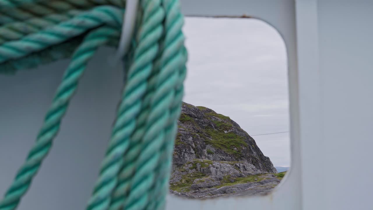 Detail eines gewundenen Tauwerks auf einem Schiff mit Bergen im Hintergrund in Norwegen