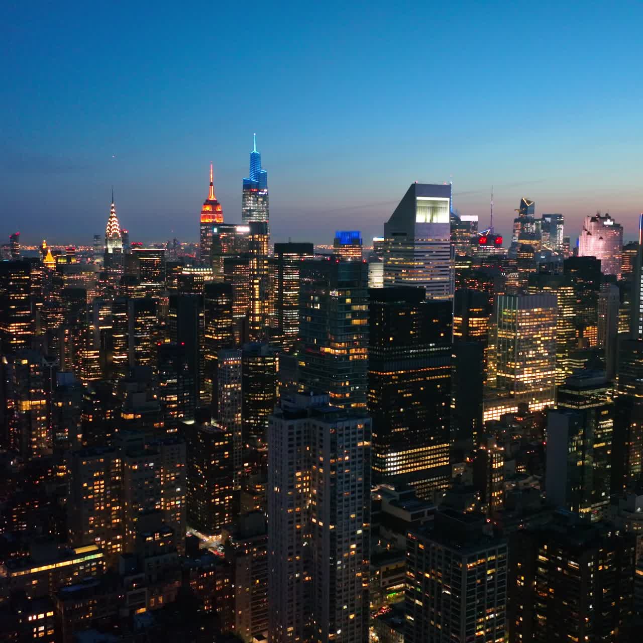 Amazing New York city full of lights in the evening. Beautiful shining skyscrapers at the backdrop of blue evening sky