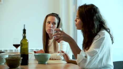 dos mujeres alegres hablando mientras beben vino