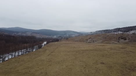 Drone-shot-of-the-forest-and-a-country-icy-river-in-the-late-autumn