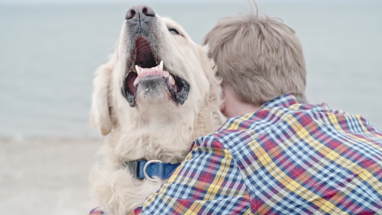 un niño adolescente abrazando a un golden retriever