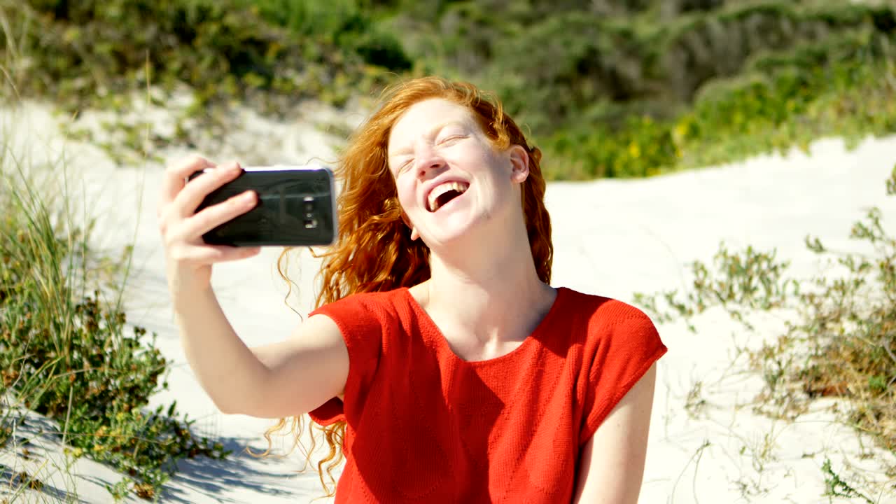 mujer tomando una selfie con teléfono móvil en la playa 4k