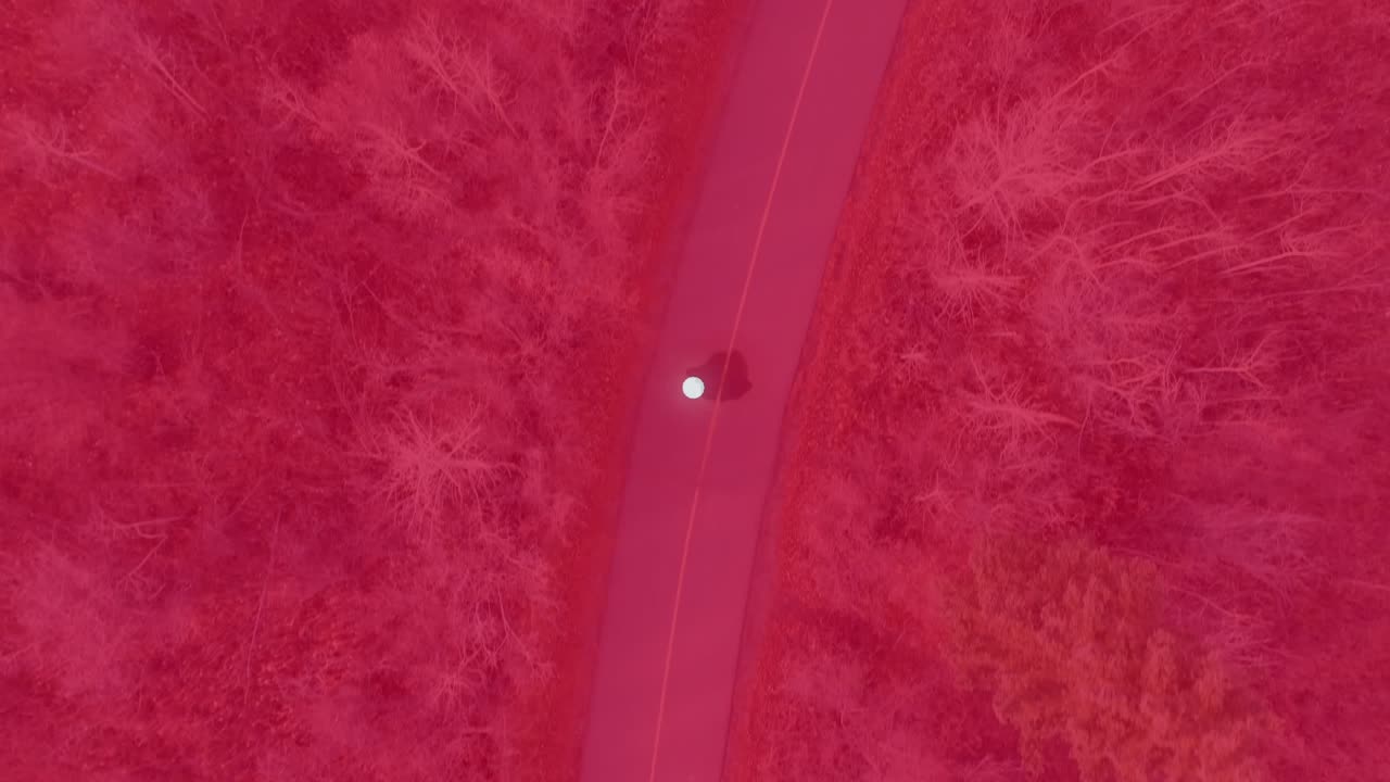 White dot breaking into triangle shards forming faceted band flowing down road to show triangles