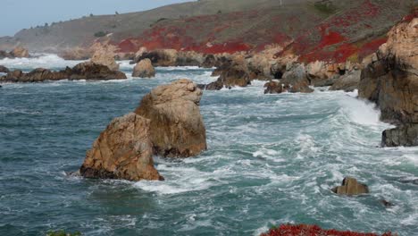 Plano-Medio-De-Grandes-Olas-Rompiendo-Contra-La-Costa-Irregular-De-Big-Sur-En-Garrapata-Con-2-Grandes-Rocas-En-Primer-Plano-En-Cámara-Lenta