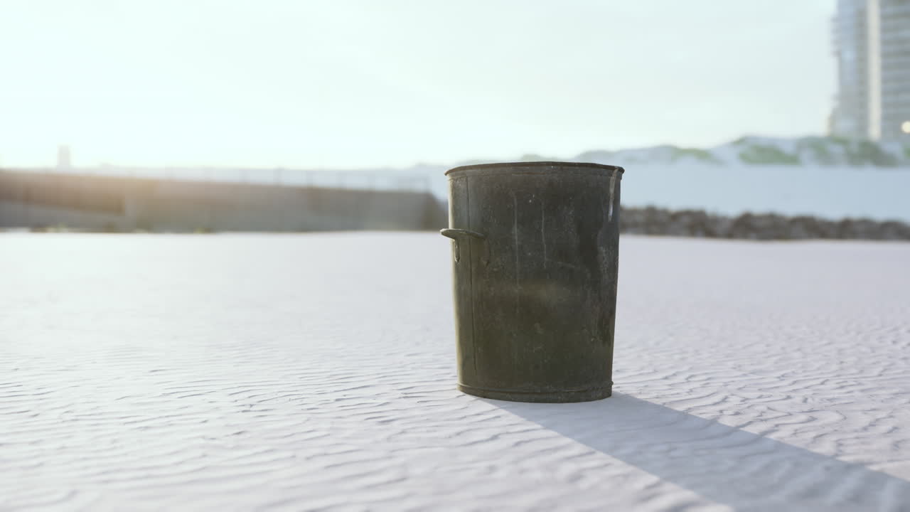 Bidone della spazzatura o cestino in metallo grigio sulla spiaggia