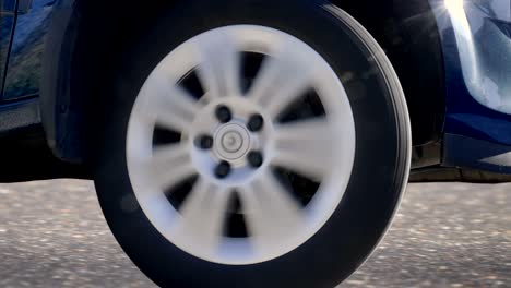 a car wheel with a shiny silver rim rides, turns to the right, to the left