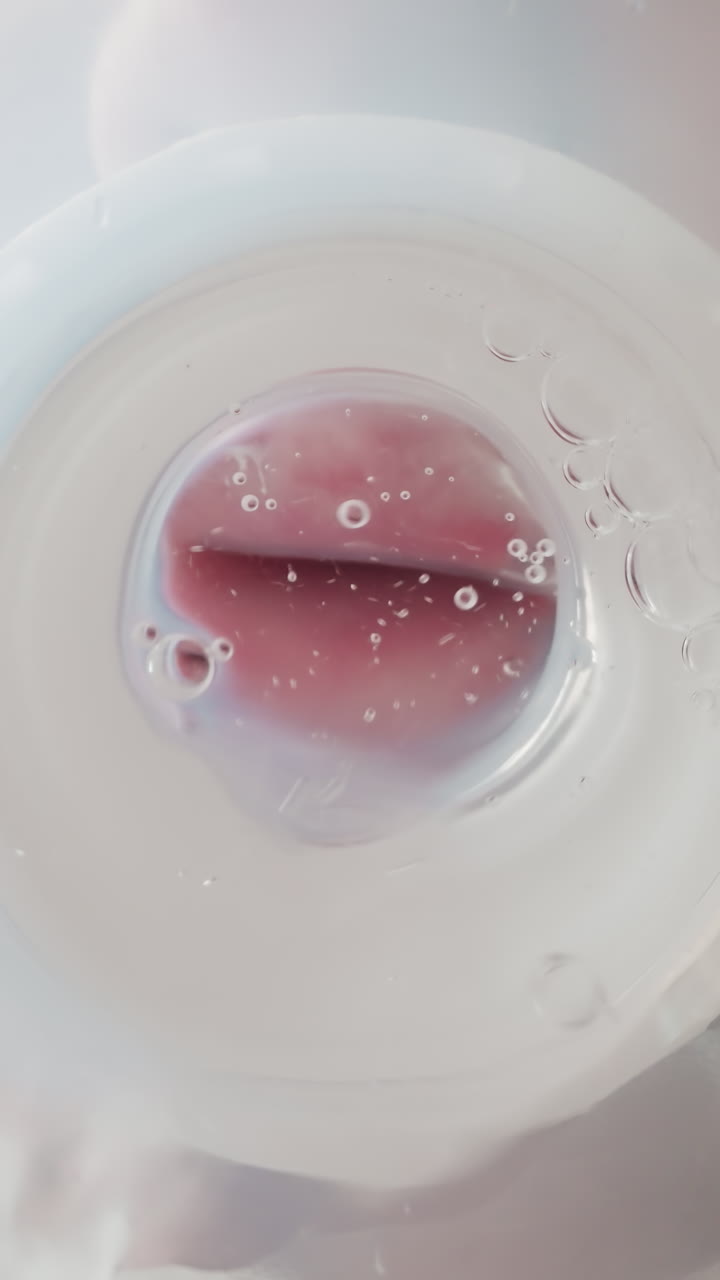 Preschooler drinks clear water from bottle with nipple swallowing actively. Air bubbles appear on waves moving towards mouth macro low angle shot