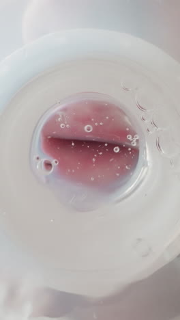 preschooler drinks clear water from bottle with nipple swallowing actively. air bubbles appear on waves moving towards mouth macro low angle shot